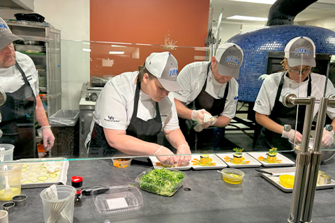 Four chefs concentrating hard while preparing their chosen meal at the ACF Culinary Competition.