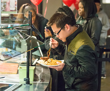 Student adding sauce to his all-you-can-eat dish