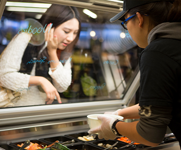 Associate creating a noodle bowl for a student, who is choosing her own customizations