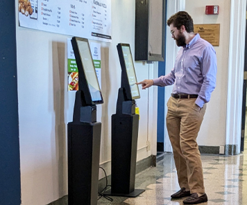 Customer ordering on the TAPAS ordering kiosk in front of Harriman Café