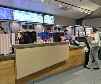 Student ordering from the Perks counter overlooking the digital menuboards