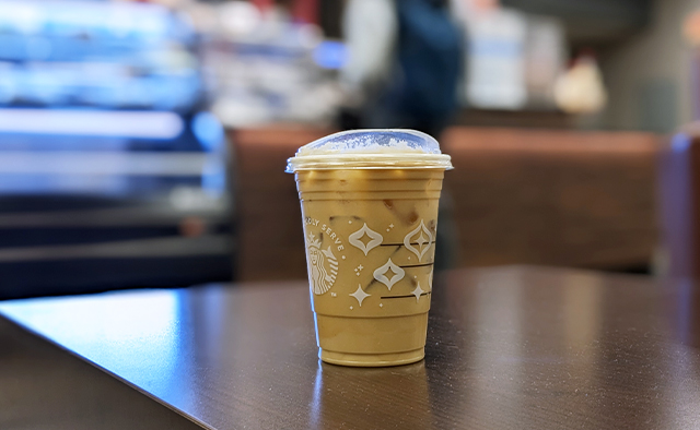Iced coffee with flavor shots sitting at a table, with Whispers Abbott counter in the background