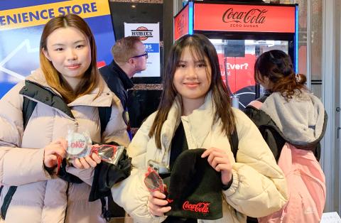 Two female students with their prizes from the Coke claw machine