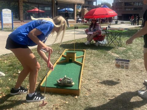 Student placing the golf ball preparing to hit it with her golf club