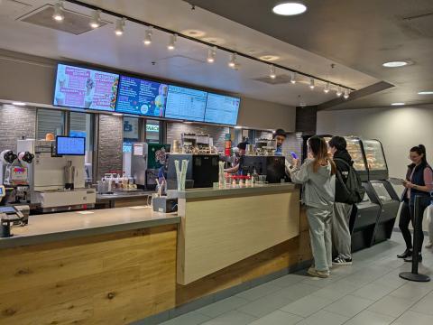 Students lining up at Perks order counter; The digital sign menuboards are behind the counter.