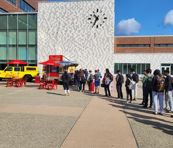 Coca-Cola Throwback truck from the side. Employees serving free Coke floats to students in a long queue.