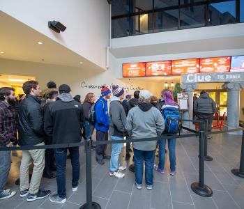 Students queuing up outside C3 for dinner, featuring the digital signage in the lobby customized for the event