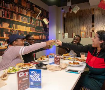 Students clinking their Clue branded glasses together at dinner for a cheer