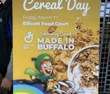 Poster that reads National Cereal Day: Friday March 7th. Ellicott Food Court. General Mills. Celebrating Cereal Made in Buffalo.
