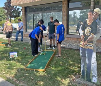 Students playing mini golf, cardboard cut out of a character from Happy Gilmore is to the side