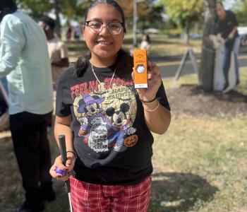 Student posing with a golf club and her prize of a pack of golf balls