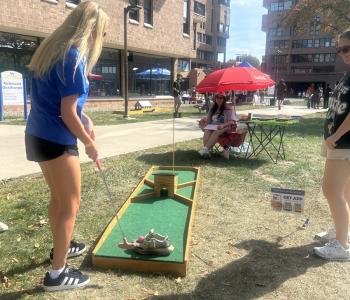 A student about to hit a golf ball with her golf club at mini golf
