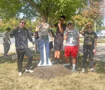 Students posing with a cardboard cut out of a character from Happy Gilmore