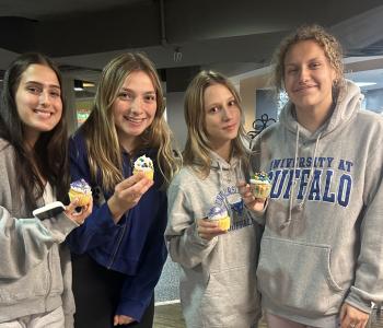 Four students showing their decorated cupcakes