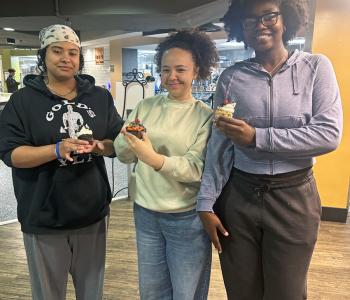 Three students showing their decorated cupcakes