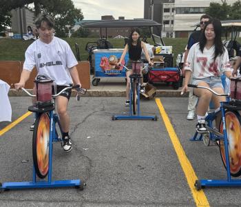 Three students riding blender bikes
