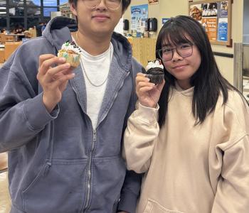Two students showing their decorated cupcakes