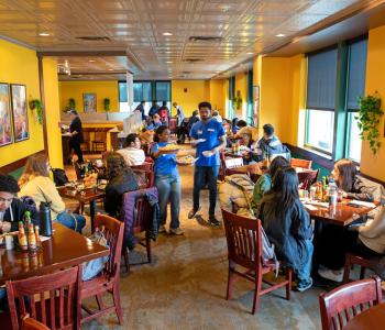 Associates serving food to students seated at Sabor Latino. Photo by Meredith Forrest Kulwicki.