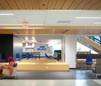 A student sitting in a seating area in front of One World Café. Photo by Douglas Levere.