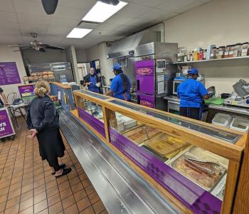 Inside NY Deli & Diner, associates are chatting with each other while preparing food.