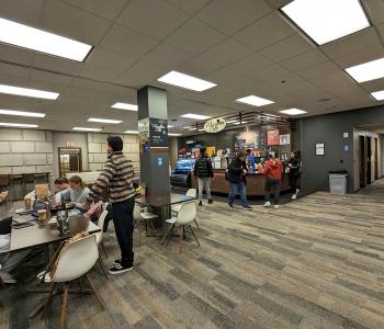 Students eating at a table and ordering at Whispers Café at Abbott Library.
