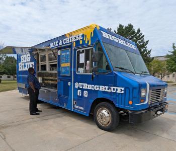 Big Blue food truck parked on South Campus. A customer is ordering food.