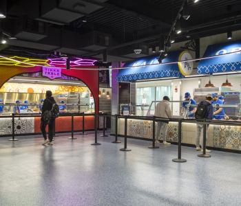 Tikka Table and Kali Orexi are at the right side of One World Café near the entrance.