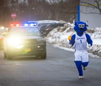 Victor E. Bull escorting the torch outside of Ellicott Complex. Photo: Meredith Forrest Kulwicki