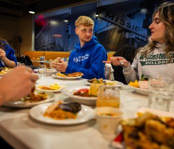 Students sitting and talking around plates of international food during the event. Photo: Meredith Forrest Kulwicki