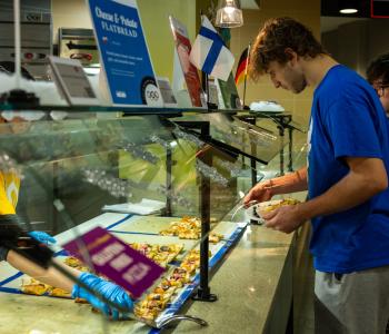 Student retrieving a slice of Polish cheese & potato flatbread at the pizza station. Photo: Meredith Forrest Kulwicki
